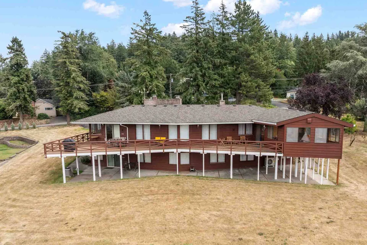 A large wooden deck surrounded by trees, with the house's exterior visible. The deck appears inviting and serene, ideal for gatherings or quiet moments. The natural setting and ample outdoor space reinforce the idea of sanctuary and privacy.