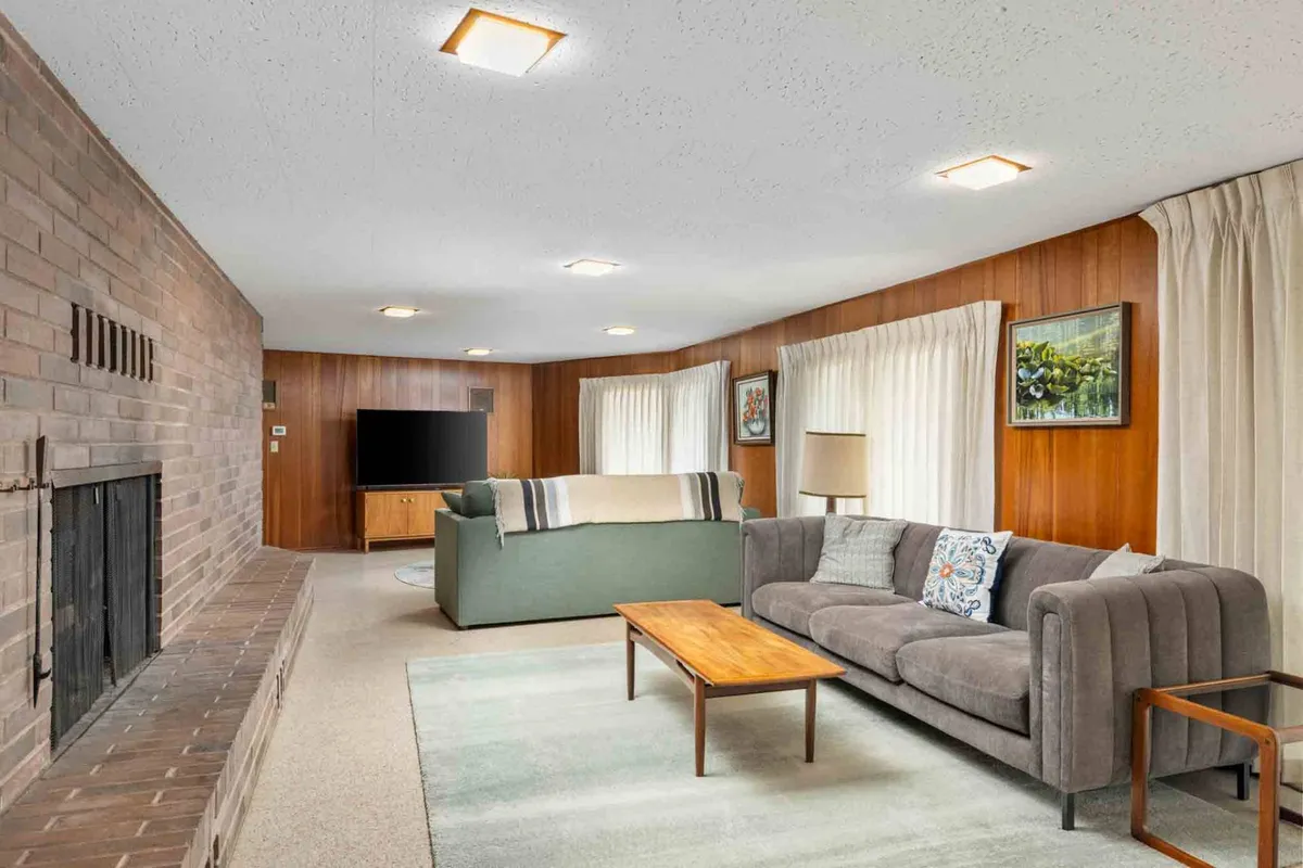 A cozy interior living area featuring a fireplace, plush sofas, and a coffee table, arranged in a way that encourages togetherness and relaxation. The space is expansive and uncluttered, suggesting room for pets to comfortably join their owners while indoors.