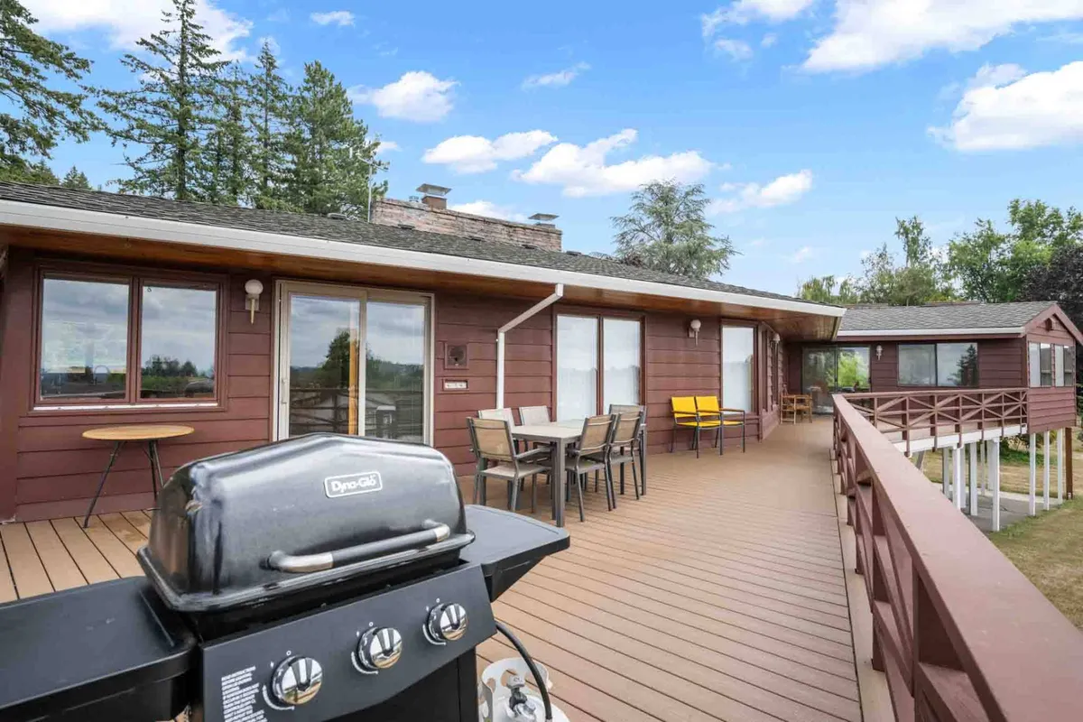 A stylish deck area featuring comfortable outdoor seating, a modern grill, and large windows framing the inviting interior. The mood is casual and welcoming, making it ideal for barbecues, morning coffee, or evening stargazing.